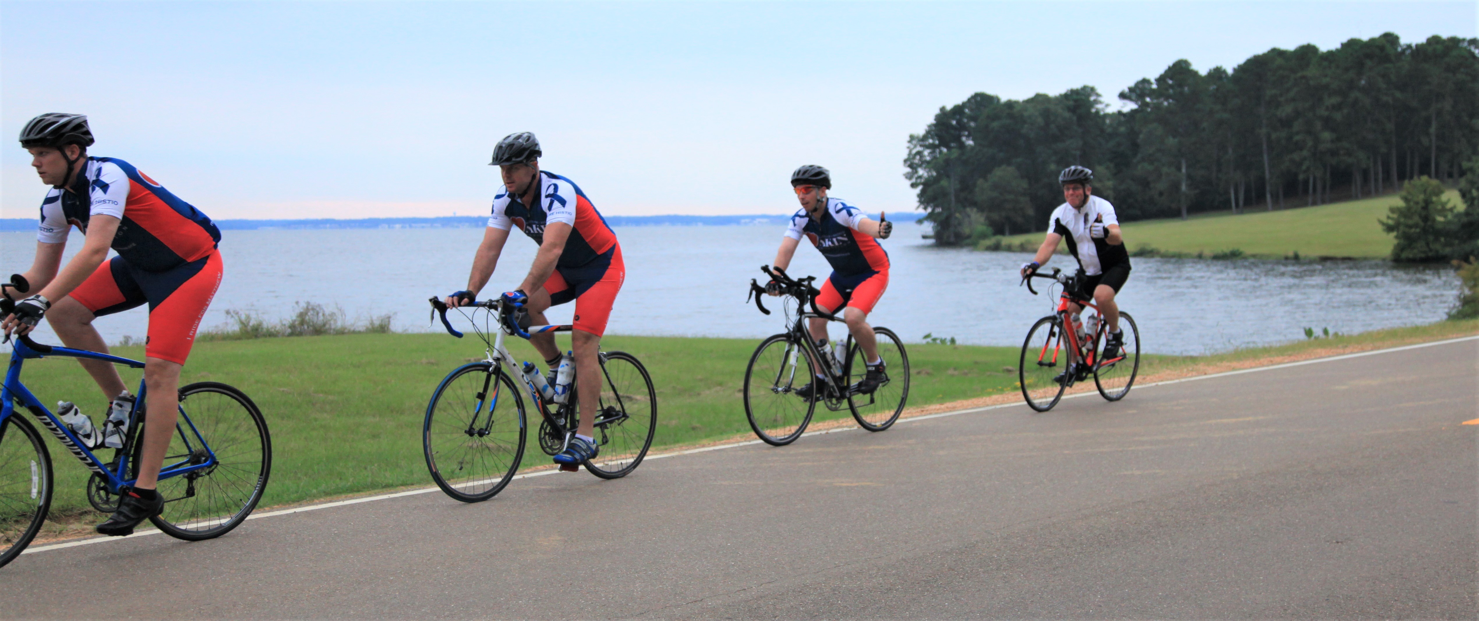3 bicycle riders pass a lake during 700-mile HLH fundraising ride