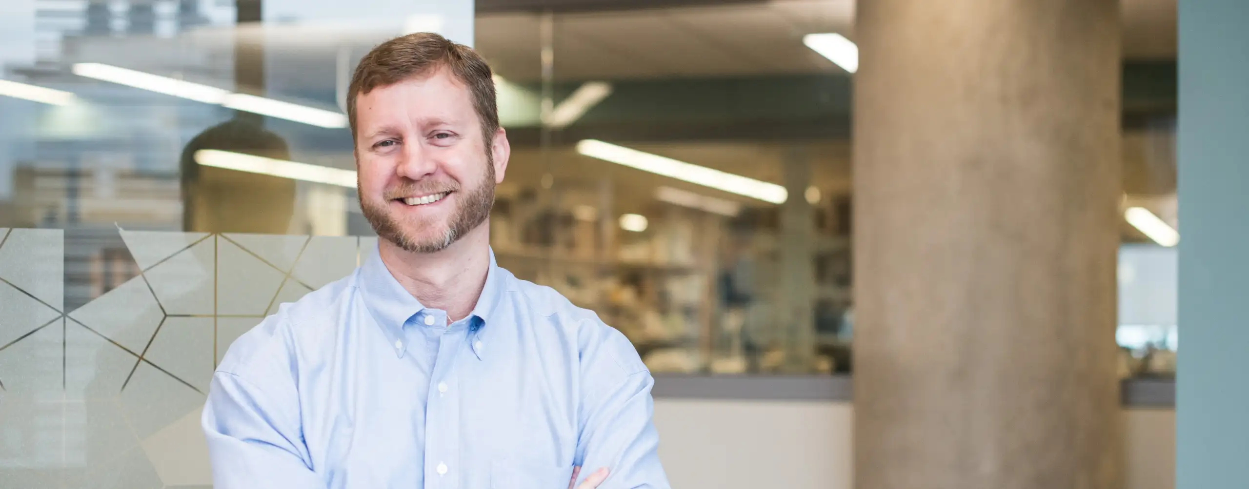 Scientist in blue shirt stands near a glass-walled conference room at Cincinnati Children's