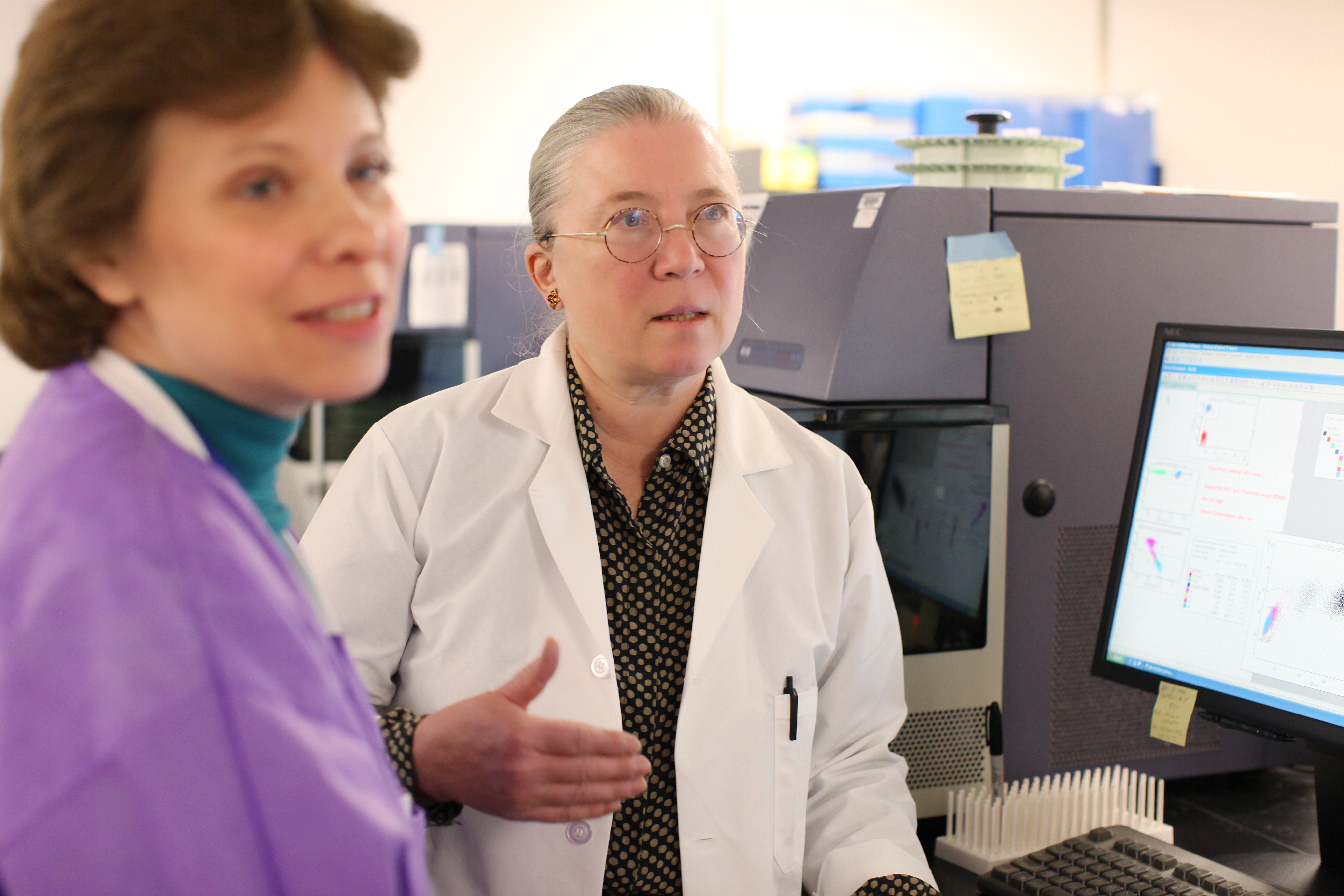 Lisa Filipovich, MD, shown in a white lab coat, consults with colleagues in her lab at Cincinnati Children's