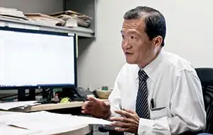 Scientist in white shirt and black tie sits near computer terminal during interview about sleep disorder treatment at Cincinnati Children's