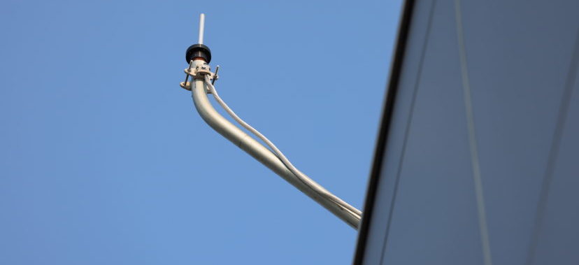 distant shot of a roof edge with a monitoring device mounted on a metal conduit