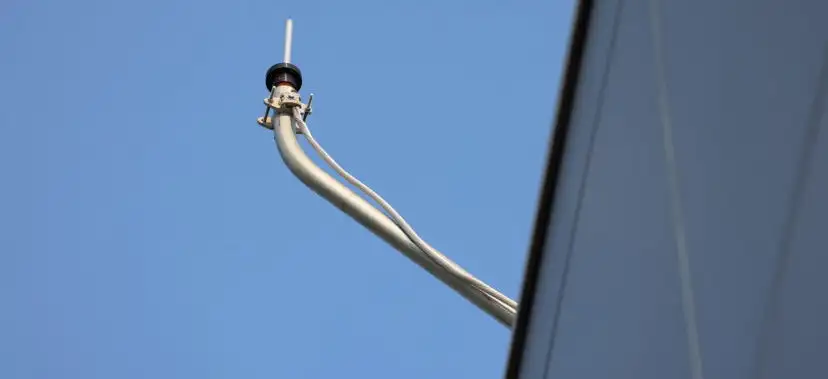 distant shot of a roof edge with a monitoring device mounted on a metal conduit