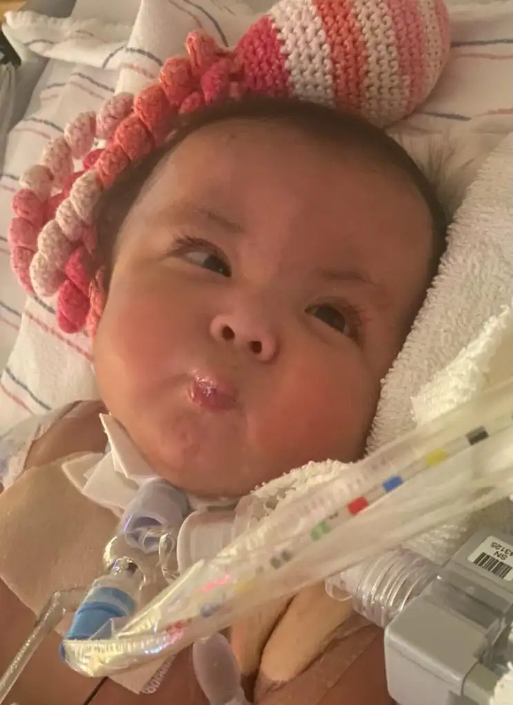 Thessa blowing tiny bubbles as she lays in hospital bed.