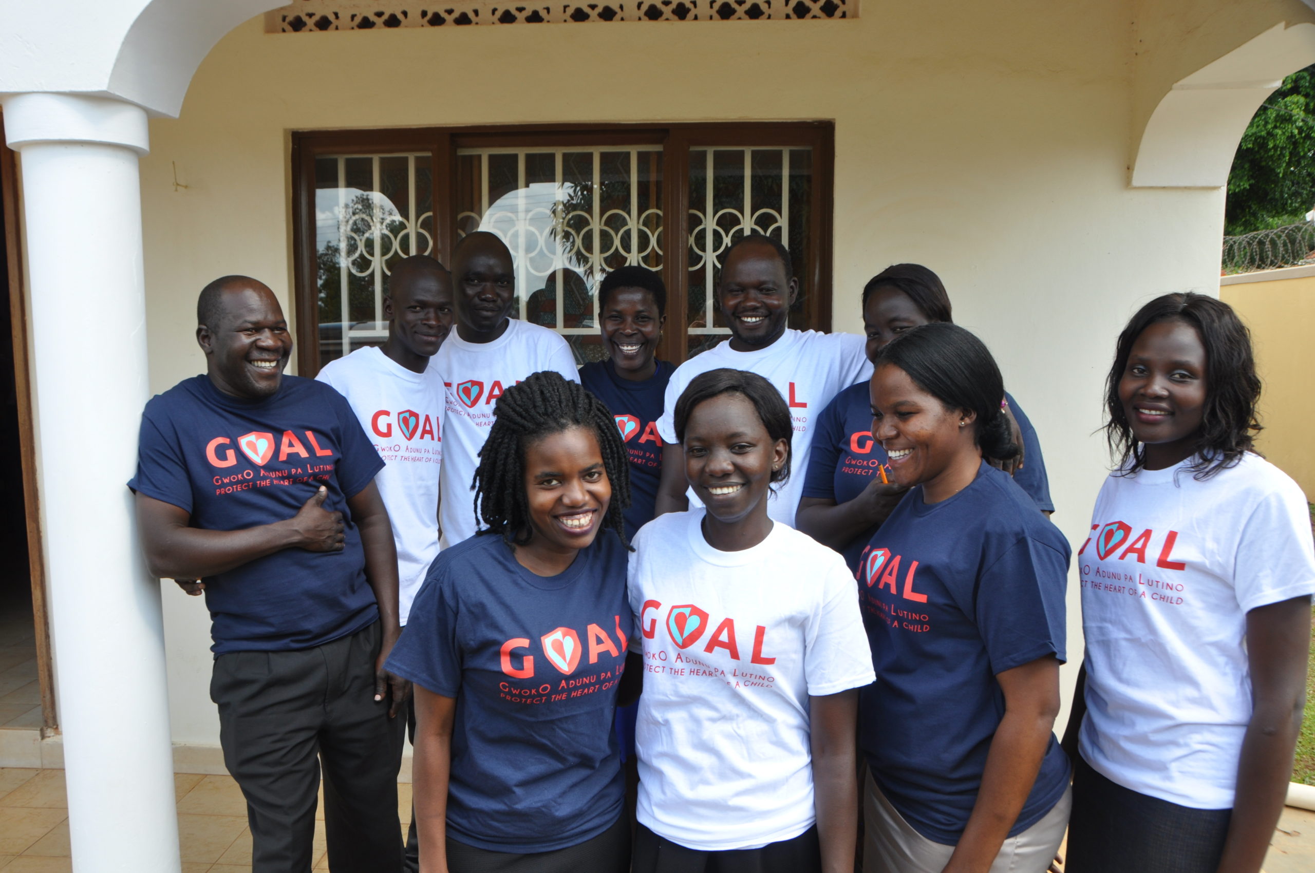 A group of GOAL study trainees gather for a group shot wearing t-shirts with the GOAL study logo