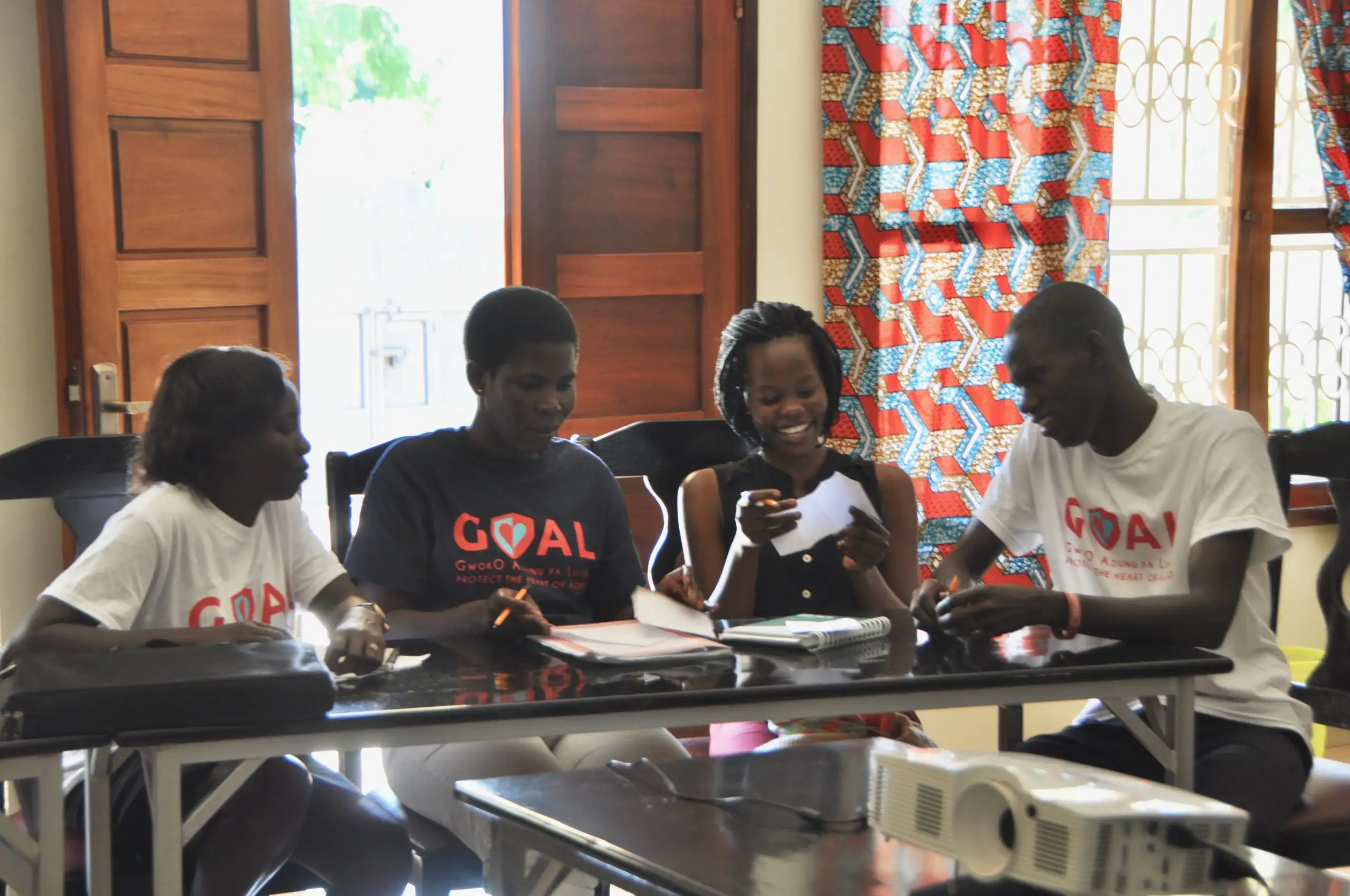 Four trainees at a table learning about the GOAL study.