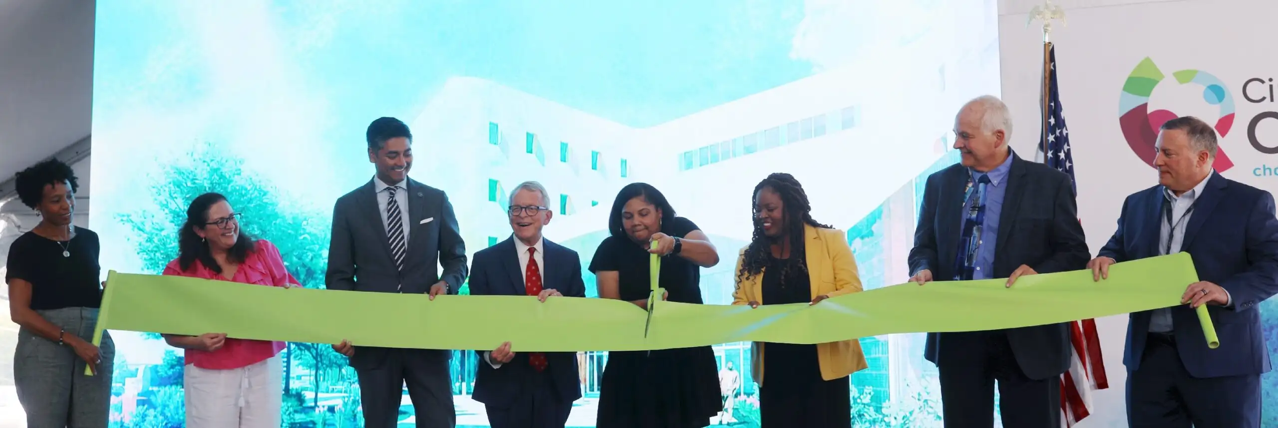 Row of officials holding a large yellow ribbon.