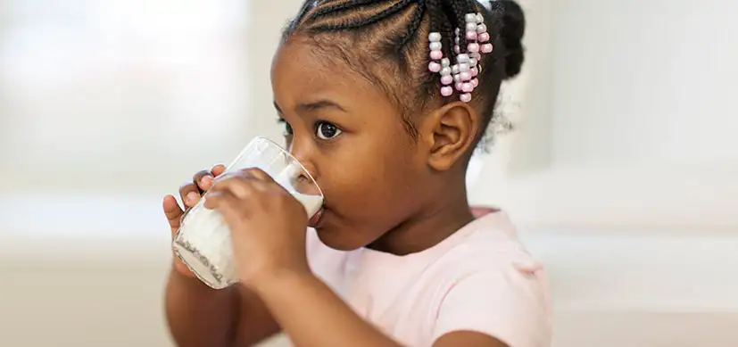 Young girl wearing pink shirt drinking milk