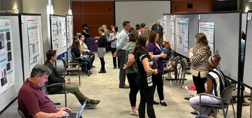 Photo of people looking at research posters in a conference hall