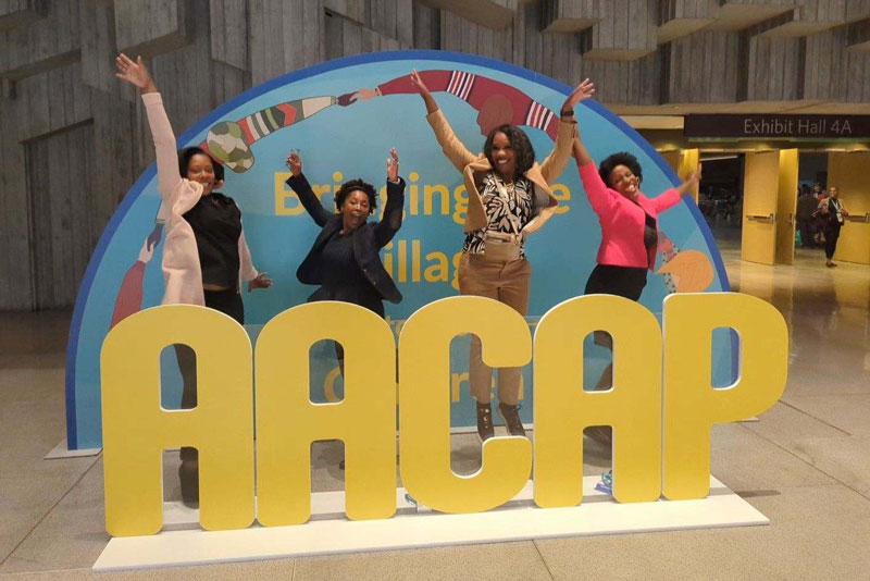 4 women jumping behind an AACAP sign