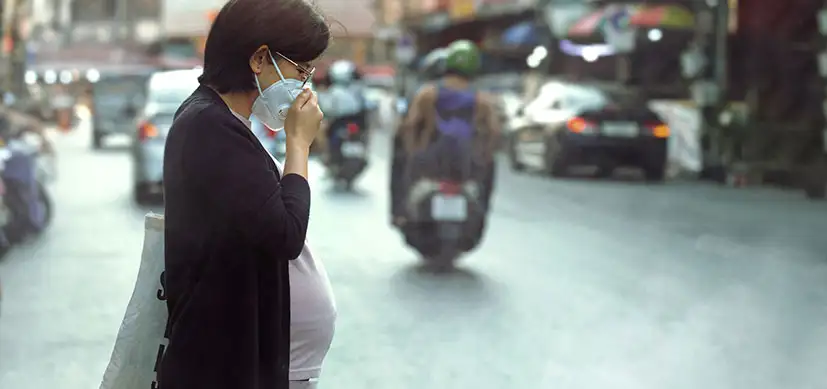 Asian woman crossing the street in a city filled with air pollution