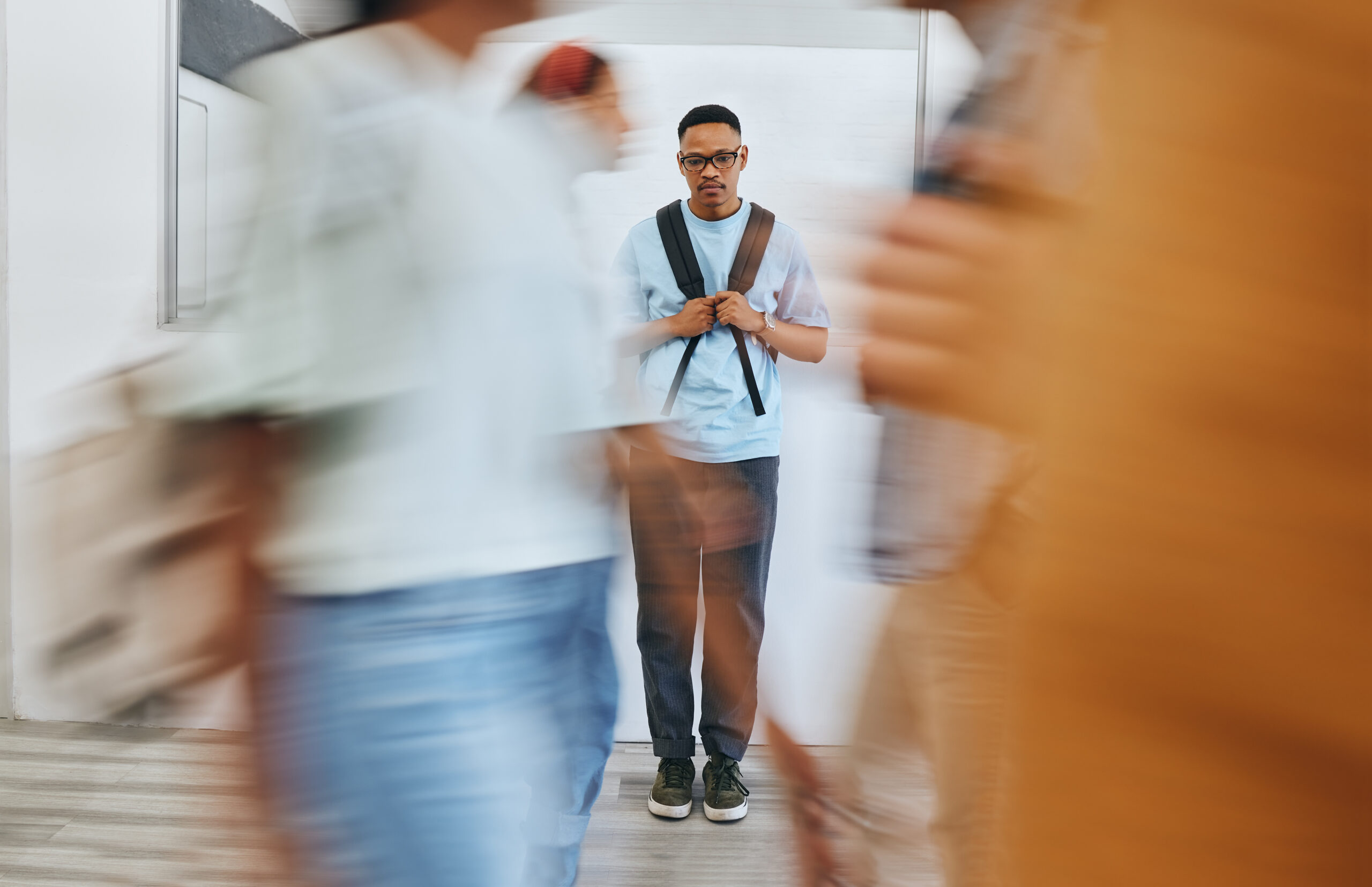 Young man alone among a blurred crowd of passersby