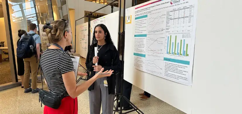 Photo of a student discussing their research poster with someone